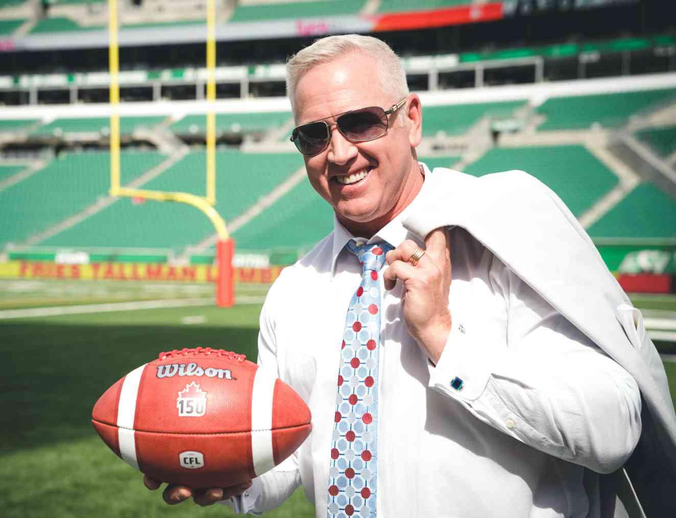 Matt Dunigan holding football in stadium