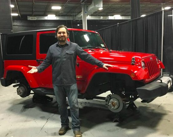 Brian Quinn posing with a jeep
