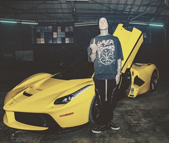 Travis Barker posing for a picture with his car in the background