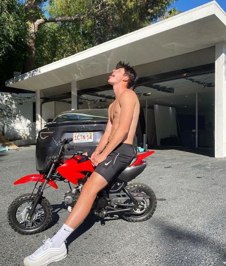 Blake Gray sitting in his toy bike with car in the background