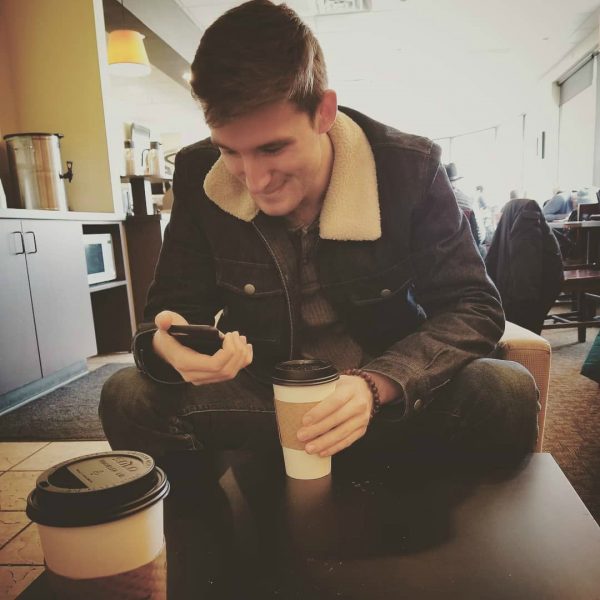 Michael Boxleitner using his phone with coffee in hand
