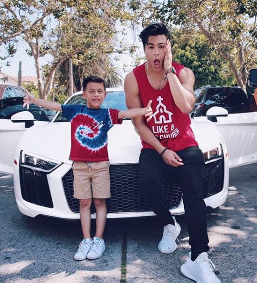 Ray Diaz posing for a photo with cars and kid