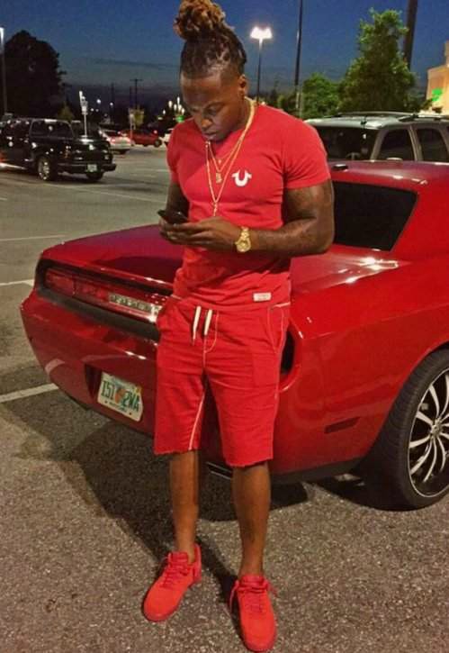 Derrick Henry using his phone while sitting outside his car