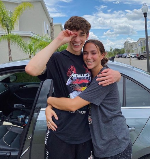 Brandon Rowland hugging his sister while car in the background