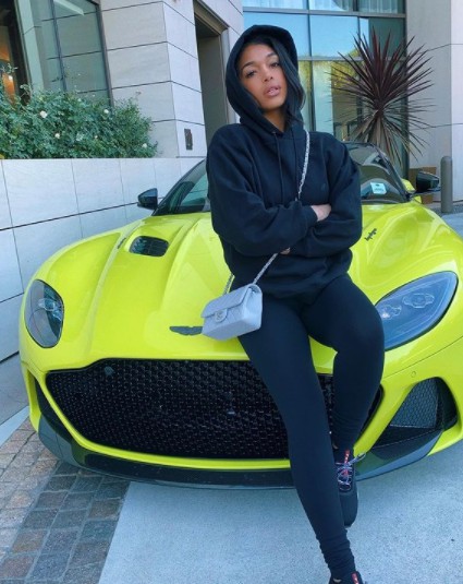 Lori Harvey posing for photo with car in the background