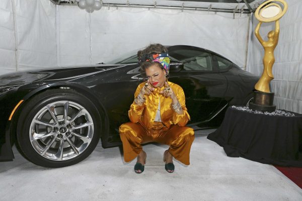 Andra Day posing for a photo with a car