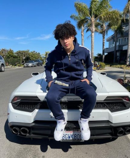 DerekTrendz posing for a photo with his car