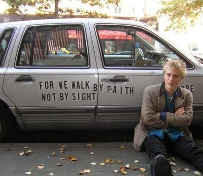 Johnny Flynn posing for a photo with his car