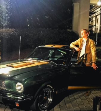 Lucas Till posing for a photo with his car