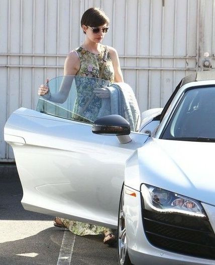 Adam Shulman's wife, Anne Hathaway posing with her car