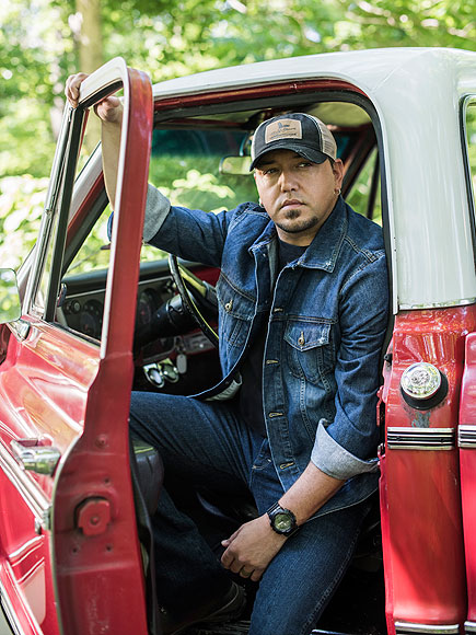 Jason Aldean posing for a photo with a car