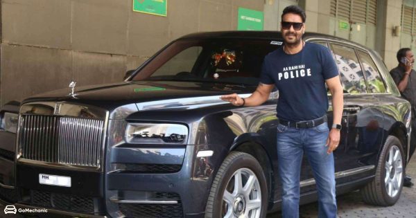 Ajay Devgan posing for a photo with car