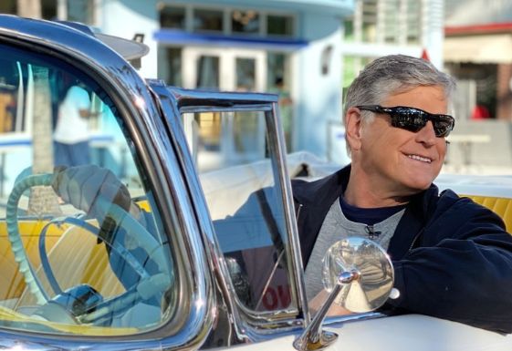 Sean Hannity posing with his car
