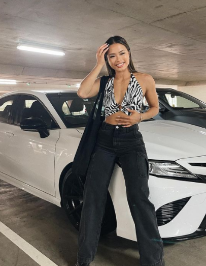 Sarah Magusara posing for a photo with her car