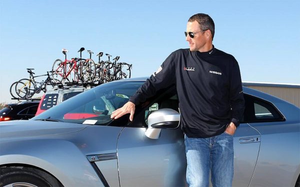Lance Armstrong posing for a photo with his car 