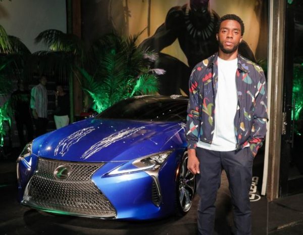 Chadwick Boseman posing for a photo with his car