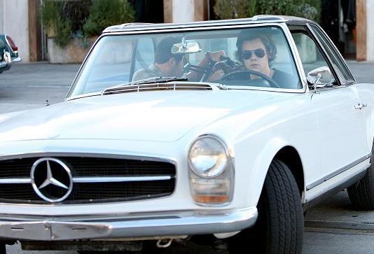 Harry Styles posing with his car
