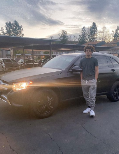 Armani Jackson posing for a photo with his car 