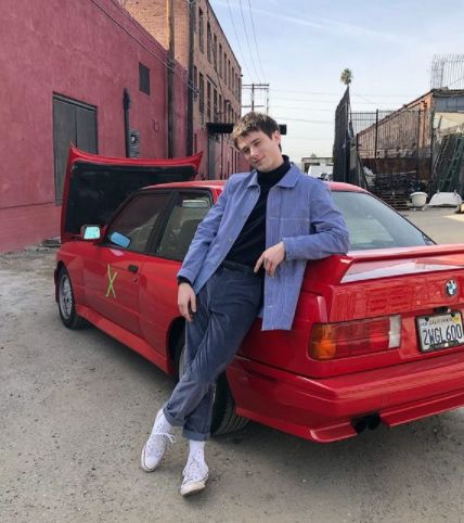 Alec Benjamin posing with his car