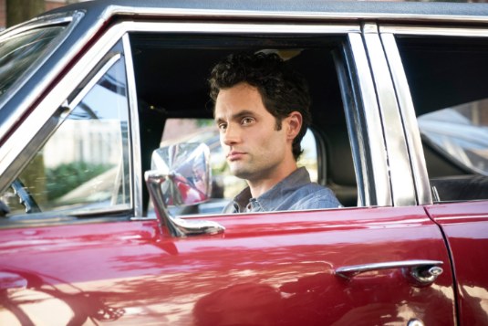 Domino Kirke's husband, Penn Badgley posing with his car