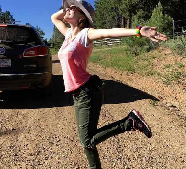 Rain Brown posing behind her car